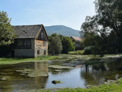 A charming stone cottage situated along the water's edge in Shieldaig, offering stunning views of the surrounding landscape.