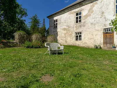 A large traditional stone cottage surrounded by expansive gardens, showcasing its classic architecture and natural beauty.
