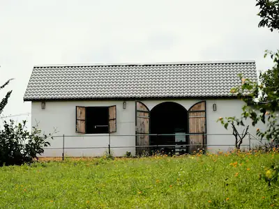 A converted barn showcasing large traditional doors and charming window shutters, blending rustic character with modern living.