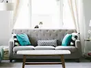 A stylish living room featuring a statement grey three-seater sofa and light colours designed to maximise natural light.