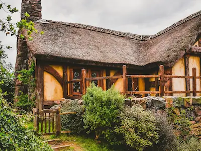 A unique thatch-roof cottage with a fairytale-like fascia, nestled within secluded gardens, offering a peaceful escape.