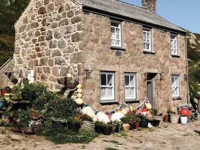 The Gardens, a charming stone cottage featuring an array of vibrant pots and fresh vegetables, showcasing a passion for horticulture.