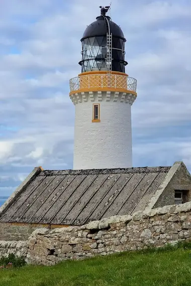 Dunnet Head Lighthouse perched on rugged cliffs, overlooking the dramatic North Sea, marking the northernmost point of mainland Scotland.