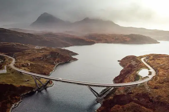 The striking Kylesku Bridge spanning the scenic Kylesku Fjord, surrounded by rugged hills and stunning coastal landscapes.