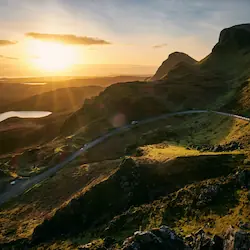 A winding hilly road near Portree, with stunning views of a shimmering lake surrounded by mountains.