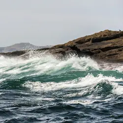 Waves crashing against the striking rocks of Staffa, illustrating the power of nature and the beauty of the coastline.